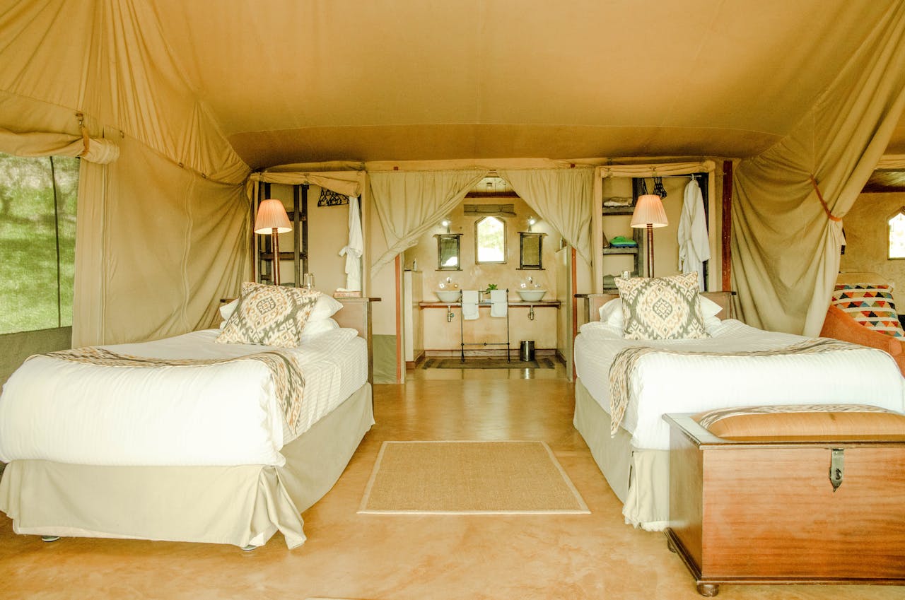 services-02 Elegant safari tent interior with twin beds and rustic decor, embodying luxury camping vibes.