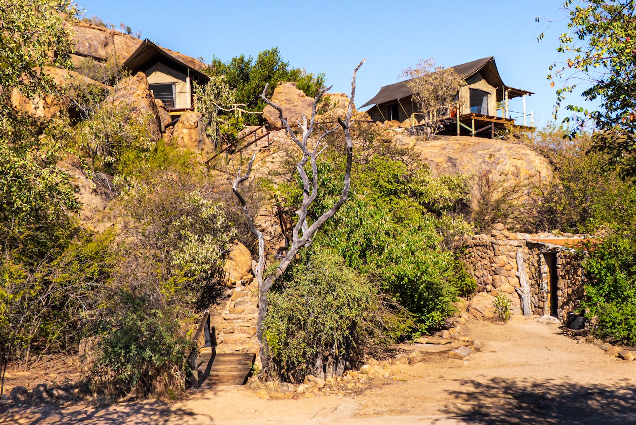 services-01 Rustic safari lodges surrounded by rocky landscape and desert vegetation, perfect for an adventurous retreat.