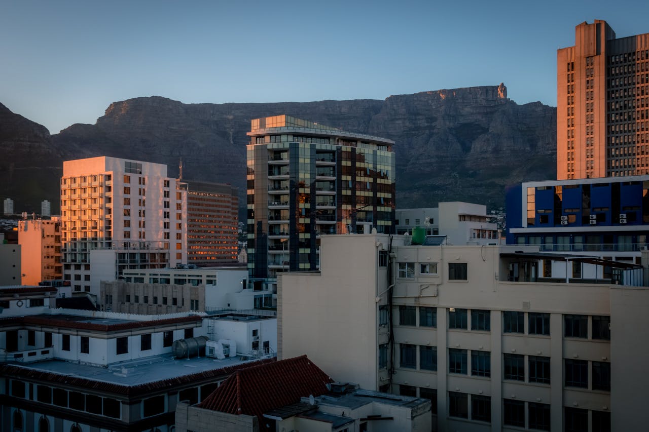 Panoramic view of Cape Town's skyline with Table Mountain at sunset, highlighting urban architecture.